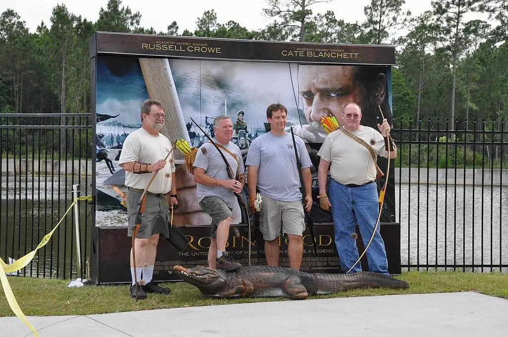Four men posing with bows and alligator