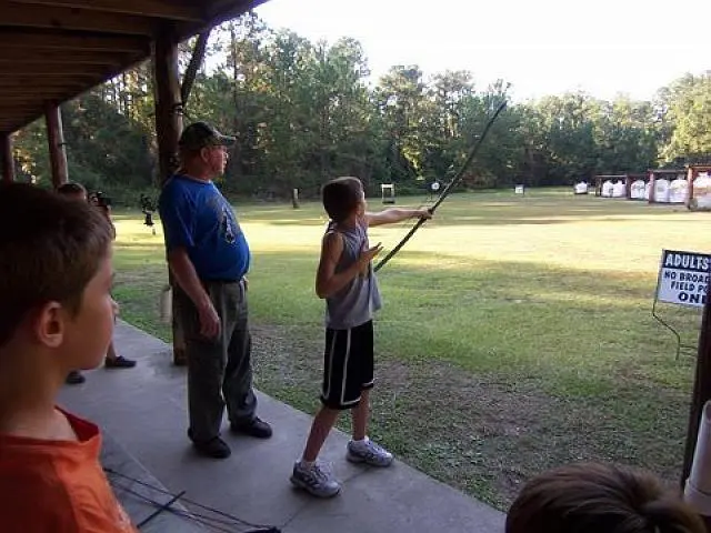 Boy shooting arrow under supervision