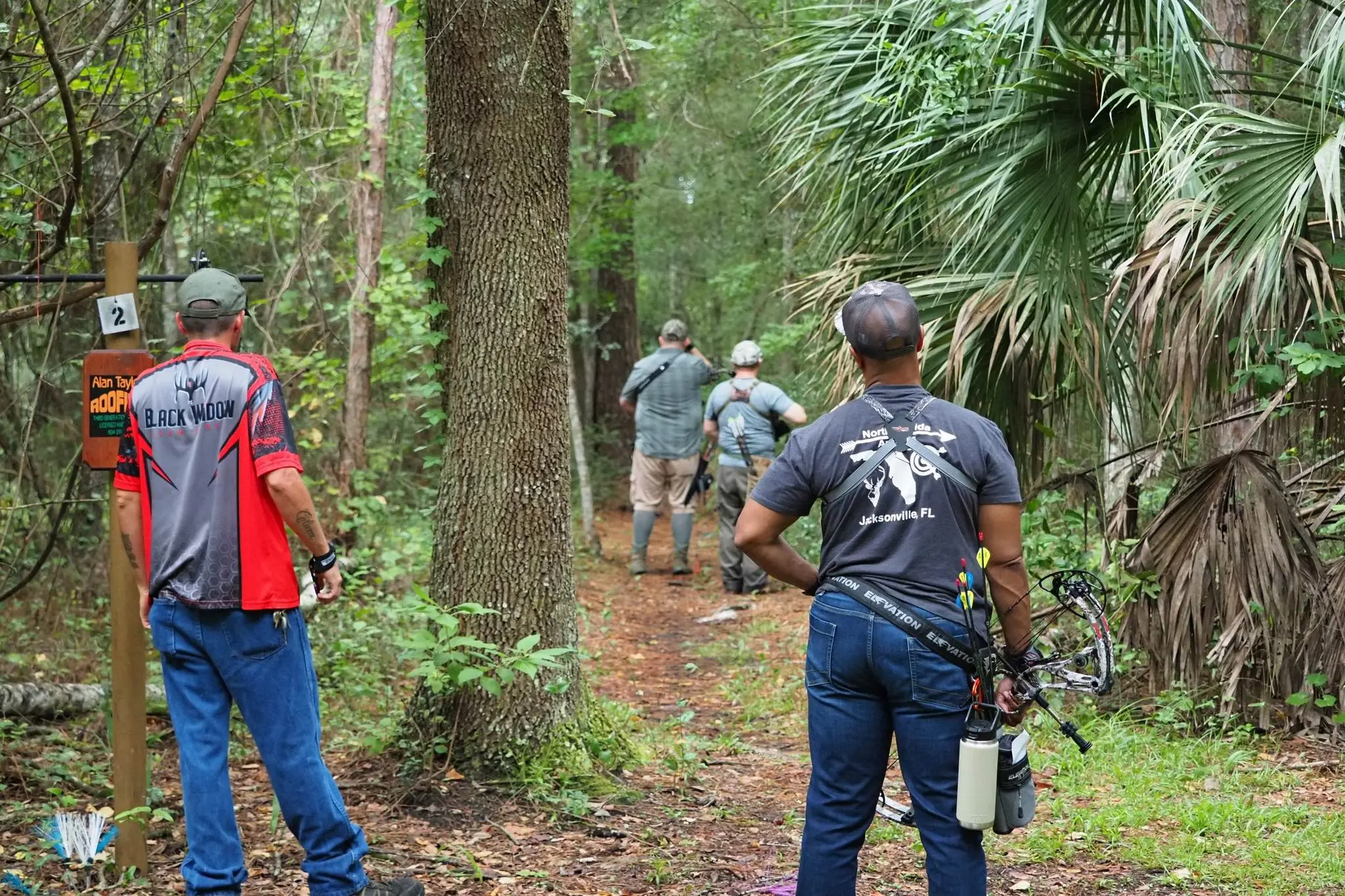 People walking through a forest trail, some holding cameras.