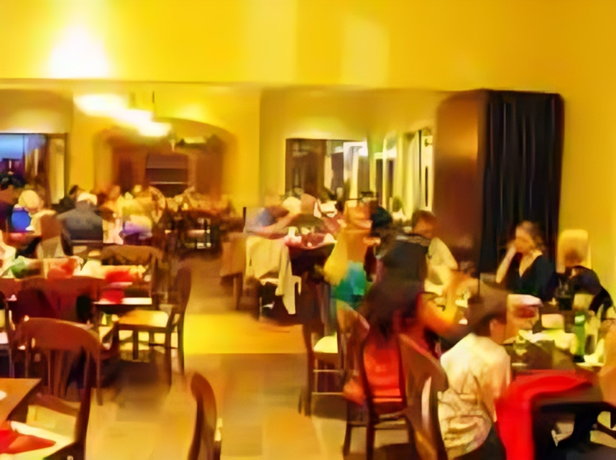 People dining in a warmly lit restaurant with yellow walls.
