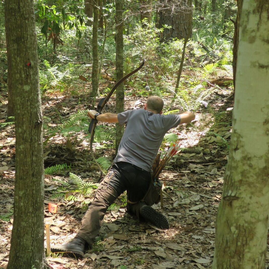 Man hiking on a forest trail surrounded by trees and greenery.